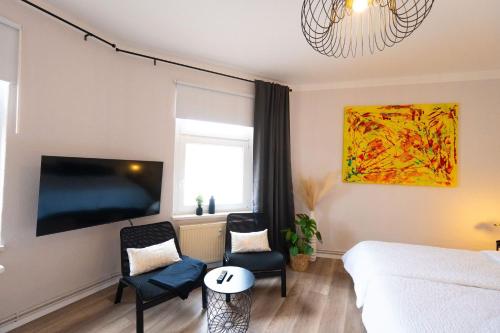 a living room with a bed and two chairs at BetterBeds City - Apartments - Zentral - Smart TV - Küche - WLAN in Brandenburg an der Havel
