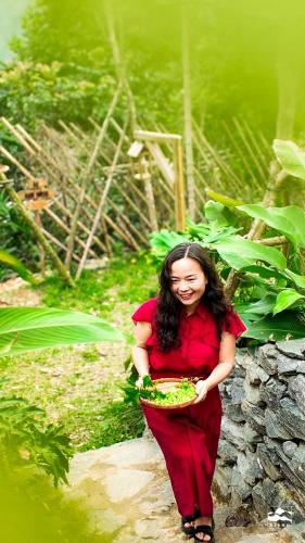 a woman is holding a bowl of greens at Xieng Retreat in Hanoi