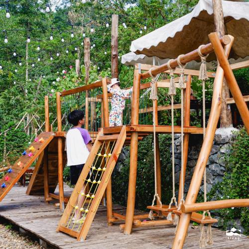 a woman is standing on a wooden playground at Xieng Retreat in Hanoi