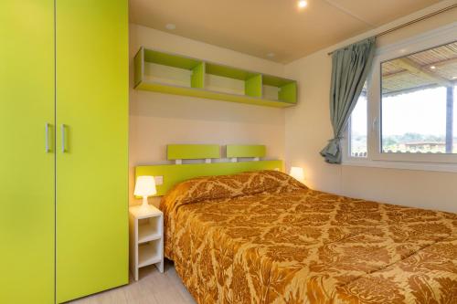 a bedroom with a bed with green cabinets and a window at Agriturismo Nonna Stella in Bibbona