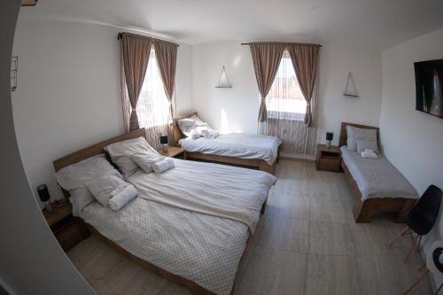 two beds in a room with two windows at Bárka Vendégház Aggtelek in Aggtelek