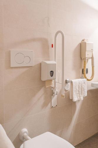 a bathroom with a toilet and towels on a wall at Crystal Hotel Varese in Varese