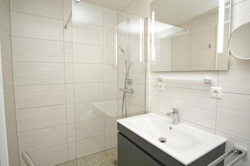Un baño blanco con lavabo y ducha. en Rex Rugia FeWo12-5 mit Schwimmbad und Saunanutzung im AHOI-Erlebnisbad Sellin, en Lobbe