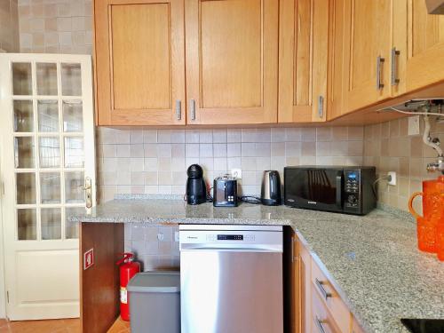 a kitchen with wooden cabinets and a white dishwasher at Mbird Rosario Family House in Cascais