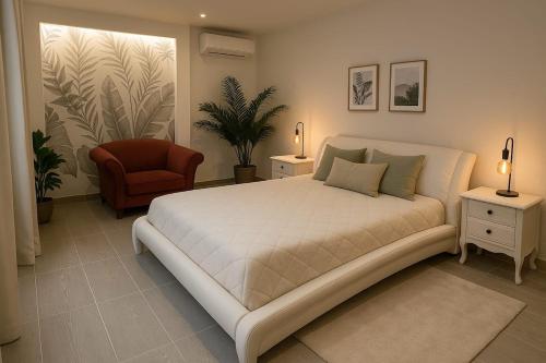 une chambre avec un grand lit blanc et une chaise dans l'établissement Charmant appartement 3 grandes chambres au coeur de Nice au calme absolu, à Nice