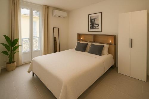 une chambre avec un grand lit blanc et une fenêtre dans l'établissement Charmant appartement 3 grandes chambres au coeur de Nice au calme absolu, à Nice