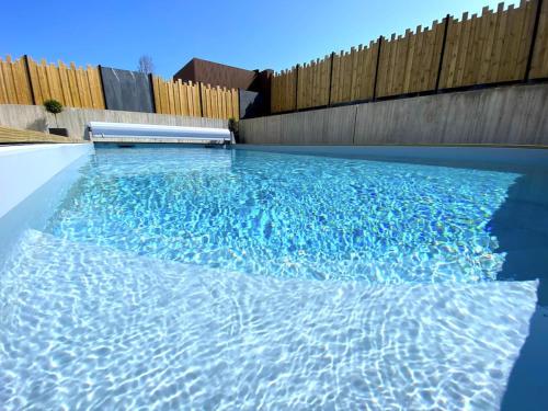 une piscine d'eau bleue devant une clôture en bois dans l'établissement Villa Au Rythme Des Marées, à Carantec