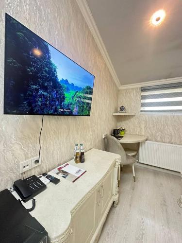 a room with a desk with a computer and a tv on the wall at Ammar hotel in Chilanzar