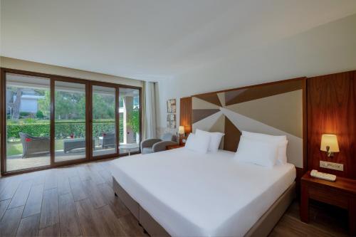 a bedroom with a large bed and a large window at Nirvana Mediterranean Excellence - Ultra All Inclusive in Beldibi