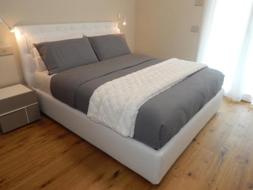 un grand lit dans une chambre avec un plancher en bois dans l'établissement Lago Dorato Roxy Apartament, à Colico