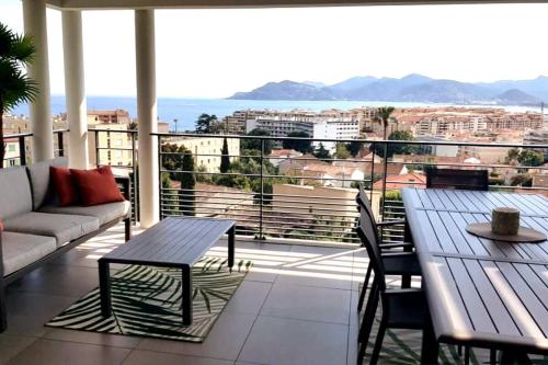 un balcon avec une table et des chaises et une vue sur l'océan dans l'établissement A096 - Superbe appartement avec vue Mer et Piscine, à Cannes