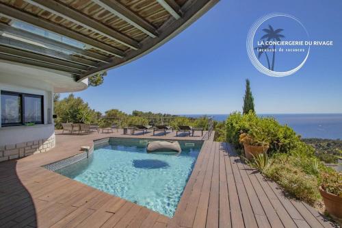 une maison avec une piscine sur une terrasse en bois dans l'établissement Villa Héméra - Vue Panoramique - Piscine - Jacuzzi, à Carqueiranne