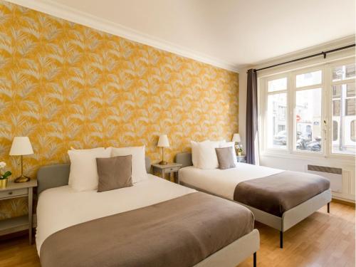 - 2 lits dans une chambre avec papier peint orange dans l'établissement Merveil - Family Suite - Champs Elysees - Mollien, à Paris
