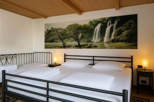 two beds in a room with a waterfall painting on the wall at Cabana Ogradena in Eşelniţa