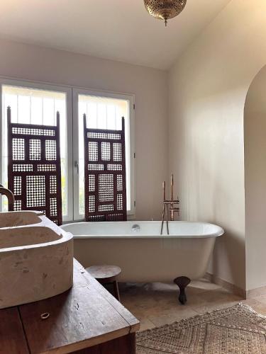 La salle de bains est pourvue d'une baignoire blanche et d'une fenêtre. dans l'établissement Chez Gui & Jisuk T6 Maison Dam Dam Léojac, à Léojac