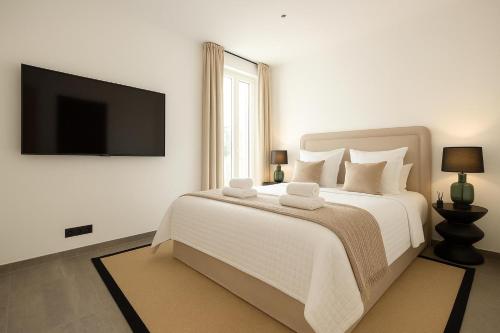 - une chambre blanche avec un grand lit et une télévision à écran plat dans l'établissement French Dolce Vita near Croisette, à Cannes