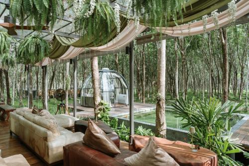 a living room with couches and trees at Timber Society Boutique Hideaway in Phuket Town