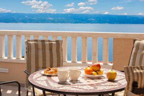 a table with a bowl of fruit on a balcony at Golden Horizon Suite in Stanići