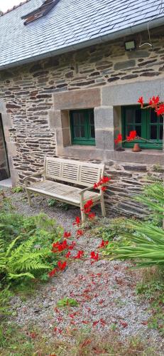 a bench in front of a building with red flowers at Stang Korvenn - Gîte du Vert Rivage in Laz