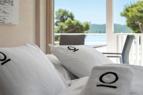 a bed with white pillows with a view of the ocean at Victorie Villa Buqez in Drage
