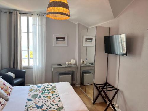 a bedroom with a bed and a tv on the wall at Hôtel Eden - La Baigneuse in Juan-les-Pins