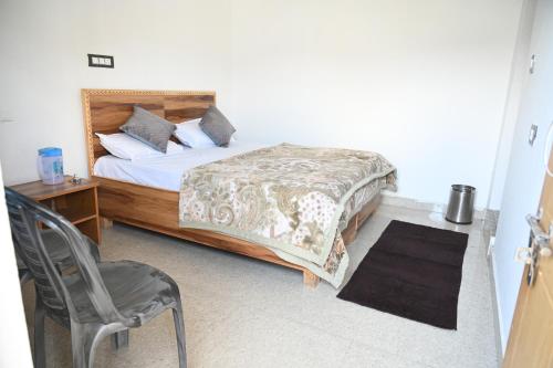 a bedroom with a bed with a chair and a table at Hotel An Himalayan View in Barkot