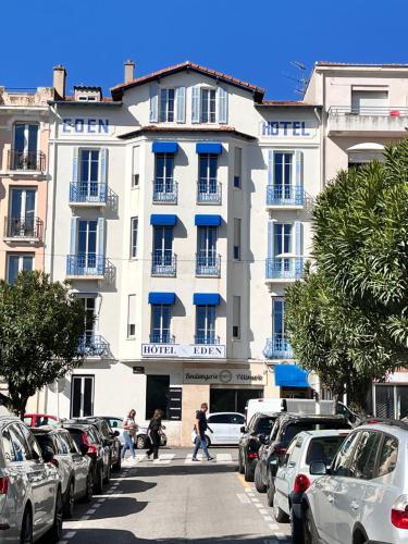 a large white building with cars parked in a parking lot at Hôtel Eden - La Baigneuse in Juan-les-Pins