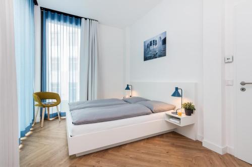 a white bedroom with a bed and a chair at smartments Berlin City West in Berlin