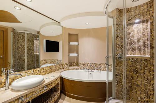 a bathroom with a tub and a shower at Gulf Hotel Bahrain Convention and SPA in Manama