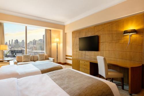 a hotel room with two beds and a desk at Gulf Hotel Bahrain Convention and SPA in Manama