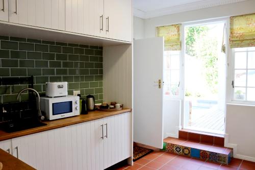 a kitchen with white cabinets and a microwave at Wholeness Accommodation in Hermanus