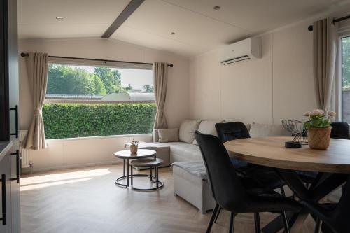 a living room with a table and a couch at Nieuw chalet Zeeland met omheinde tuin & airco nabij natuur en zwembad VP089 in Heinkensand