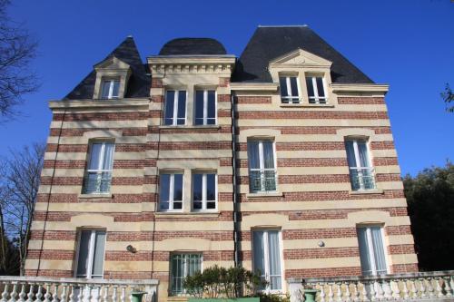 un grand bâtiment en briques avec un toit noir dans l'établissement 200m de la mer Piscine WIFI T3 38 m2 6 pers 2 chambres Ascenseur, à Cabourg