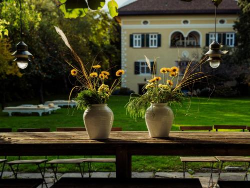 two white vases with flowers on a wooden table at Villa Arnica in Lana