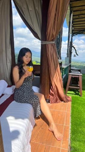 a woman sitting on a bed holding a drink at Mandhasativa Homestay in Singaraja