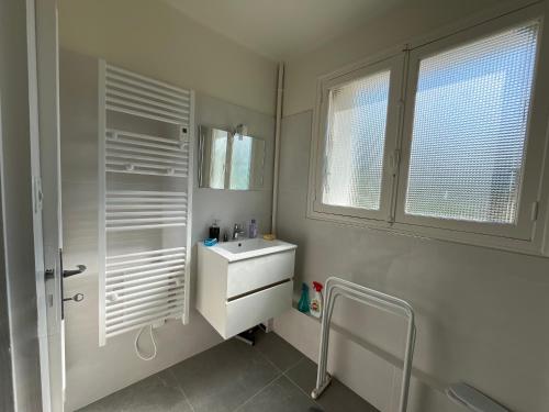 une salle de bain blanche avec un lavabo et une fenêtre dans l'établissement Il y a le ciel, le soleil, et la mer 4 chambres, à Bénodet