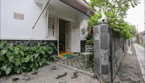 une maison blanche avec un porche et une chaise à l'extérieur dans l'établissement Comfy Room Yogyakarta BY Hamsa Putih, à Yogyakarta