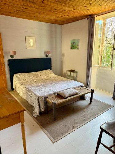 une chambre avec un grand lit et un banc dans l'établissement Domaine de la Hargue, à Manciet