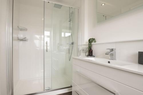 a white bathroom with a shower and a sink at Eldred Cottage in Middleham