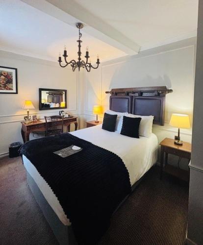a bedroom with a large bed and a chandelier at The Coleshill by Greene King Inns in Coleshill