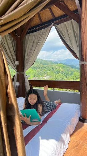 a girl laying on a bed with a laptop at Mandhasativa Homestay in Singaraja