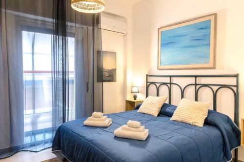Un dormitorio con una cama azul con toallas. en Casteldaci Sea house - Exclusive brand "Holiday in the CT", en Aci Castello