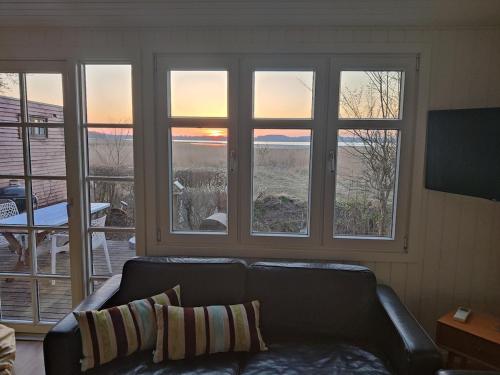 a living room with a couch and three windows at One-of-a-kind waterfront wooden house in Hejls