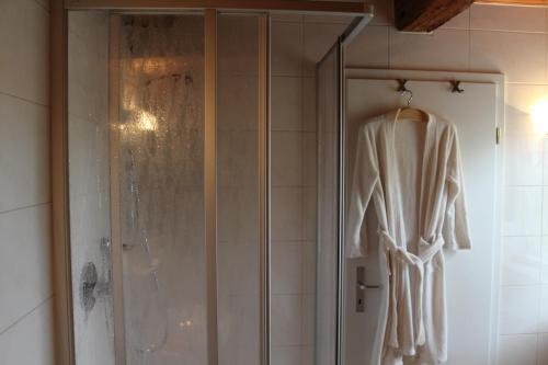 y baño con cabina de ducha y albornoz. en Gästehaus Glaubenstein, en Ebern