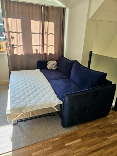 a blue couch in a room with a bed at Nybyggt modernt gästhus nära naturen in Norrköping