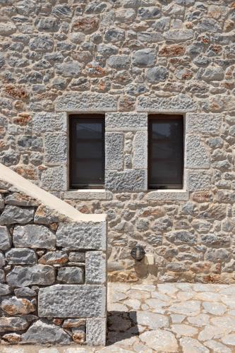 a stone building with two windows and a staircase at Petritis Guesthouse in Oítilon