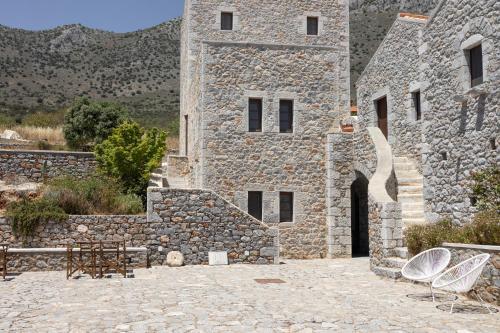a stone building with two chairs in front of it at Petritis Guesthouse in Oítilon