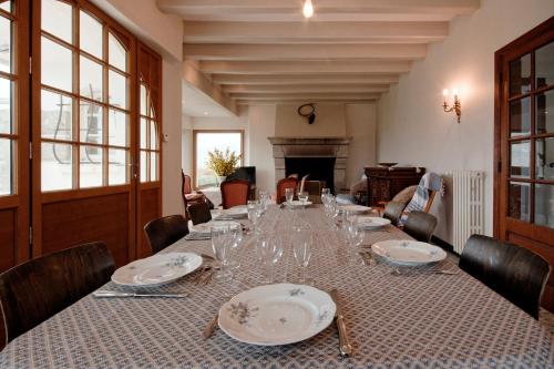 d'une salle à manger avec une grande table, des assiettes et des verres dans l'établissement La Pastourelle - 10min à pied de la plage, à Saint-Cast-le-Guildo