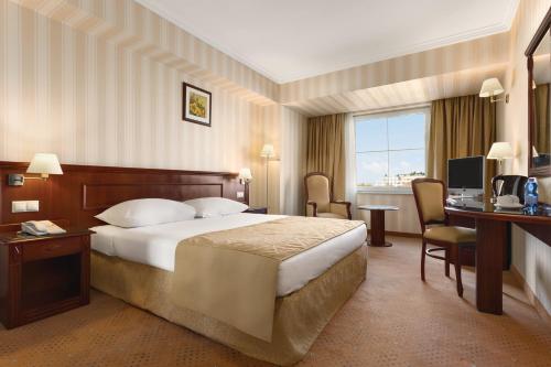 a hotel room with a bed and a desk and a television at Ramada Hotel & Suites by Wyndham Bucharest North in Bucharest