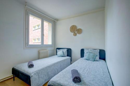 deux lits dans une chambre avec une fenêtre dans l'établissement Le Soleil Levant parking facile, à Toulouse